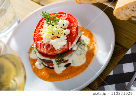 Tasty stack of fried eggplants and tomatoes on spicy sauce served at plate Tasty stack of fried eggplants and tomatoes on spicy sauce served at plate 110831029