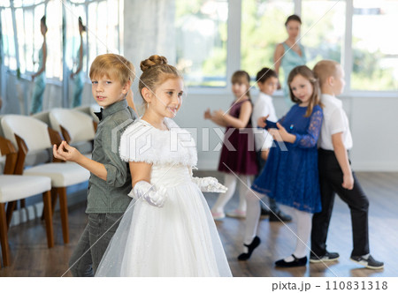 Little children in elegant dresses practicing rock-n-roll dance in school hall 110831318