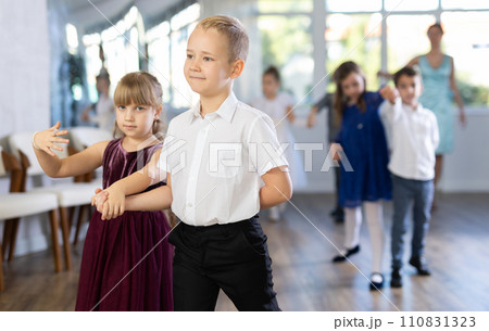 Little children in elegant dresses standing in pairs in dance pose in school hall 110831323