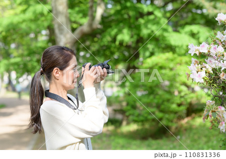 花をカメラで撮影するシニア女性 110831336