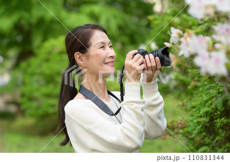 花をカメラで撮影するシニア女性 110831344