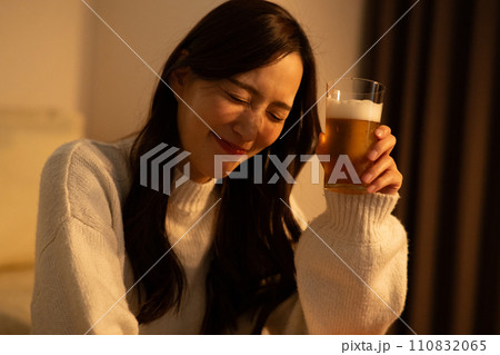 夜に部屋でビールを飲む女性 110832065