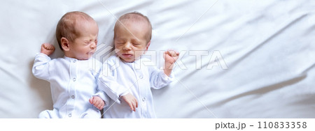 Newborn twins on the bed,on a white background. Life style, emotions of kids. Banner Newborn twins on the bed,on a white background. Life style, emotions of kids. Banner 110833358