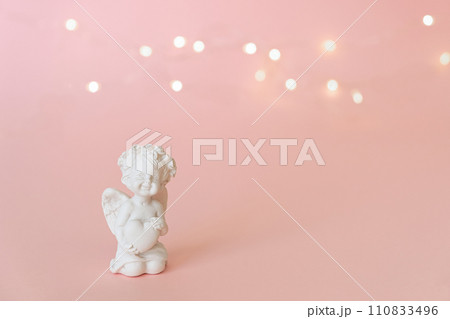 figurine of an angel Cupid with a bow on a pink background. Valentine's Day. figurine of an angel Cupid with a bow on a pink background. Valentine's Day. 110833496