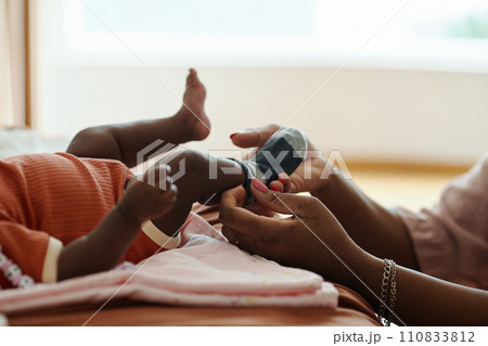 Hands of mother putting small socks on feet of newborn baby 110833812