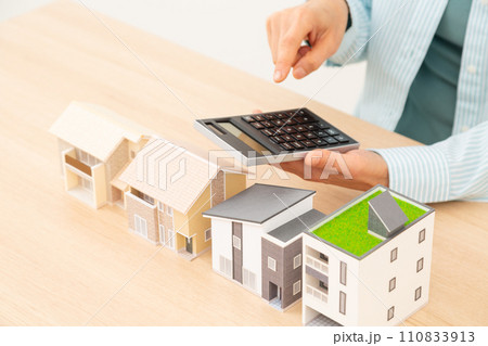 家と電卓で計算をするミドル女性 110833913