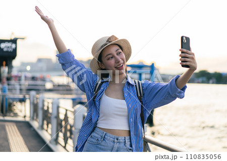 Traveler asian young woman using smart phone camera to take a selfie photo, selfie at riverside of Chaopraya River in Bangkok. Backpacker travel on holiday trip or vacation concept 110835056