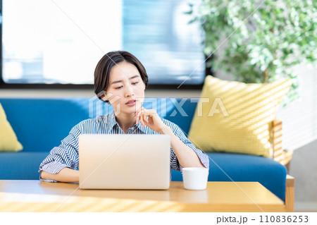 リビングでノートパソコンを操作する女性。 110836253