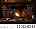 Laptop with a picture of a bonfire screen, indoor near burning fireplace in rustic style, with cozy blanket and cup of coffee. Seasonal remote work, internet, shopping. 110836343