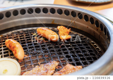 焼肉店の網で焼かれているウィンナーと牛肉 110839316