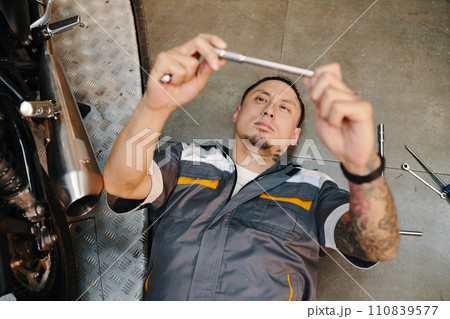 Mechanic choosing wrench to use when fixing motorcycle 110839577