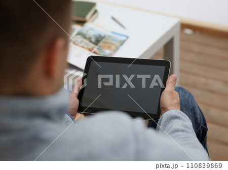 Male hand holds tablet in home setting while 110839869
