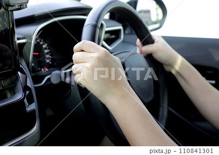 Hands holding steering wheel of car 110841301
