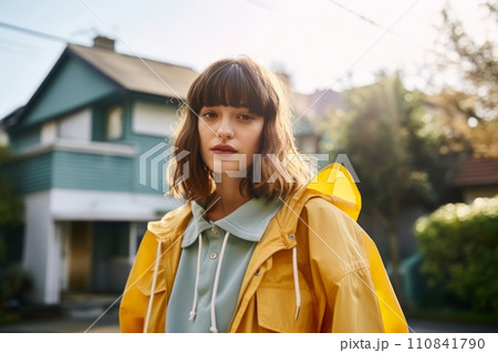 Portrait of a beautiful girl in a yellow raincoat on the street. 110841790