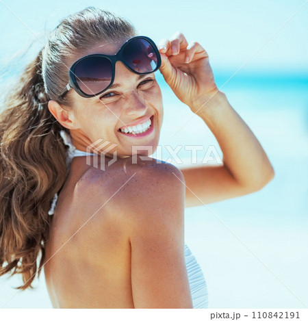 smiling woman in swimsuit with sunglasses on beach 110842191