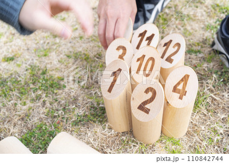 モルックのスキットルを並べる男女 110842744