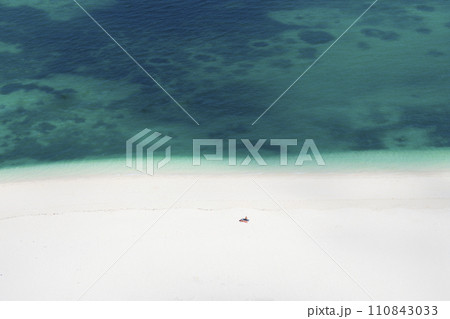 white sandy beach in the green ocean and one tourist alone 110843033