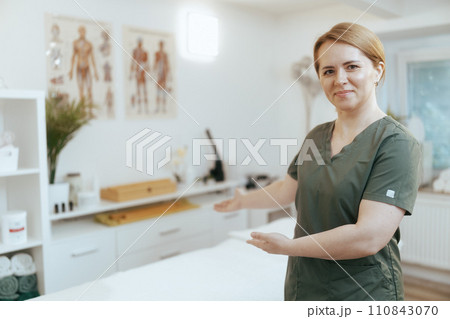 female medical massage therapist in massage cabinet welcoming 110843070