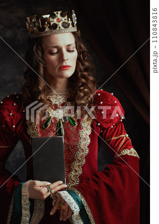 medieval queen in red dress with book and crown medieval queen in red dress with book and crown 110843816