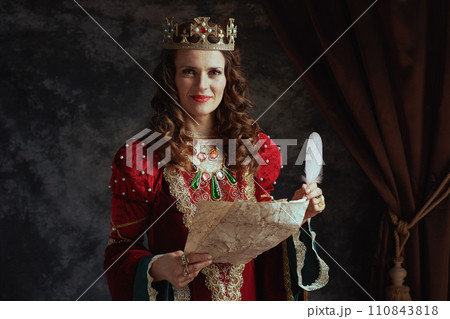 happy medieval queen in red dress with parchment and crown happy medieval queen in red dress with parchment and crown 110843818