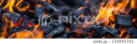 Burning firewood and coals of a fire close up 110845781