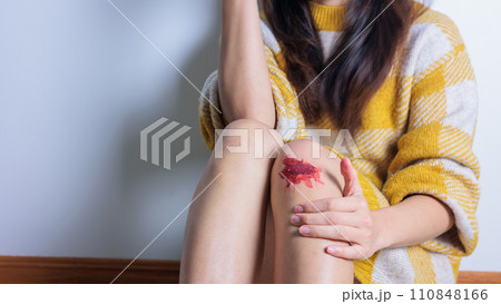 膝を擦りむいて床に座る女性（顔なし） 110848166