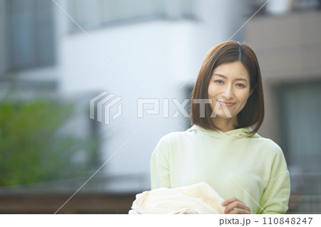 洗濯物を持つミドルの女性 洗濯物を持つミドルの女性 110848247