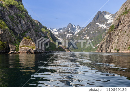 Trollfjorden's steep cliffs and mountains, with snow veins, under a blue sky and a flying bird 110849126