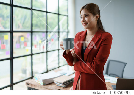 Businesswoman enjoys relaxing with a cup of coffee after a long day Businesswoman enjoys relaxing with a cup of coffee after a long day 110850292