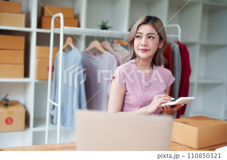 Portrait Of Asian Female Owner Of Fashion Store Checking Stock In Clothing Store With using notebook successful happy smile at small business, sme or ecommerce concepts. Portrait Of Asian Female Owner Of Fashion Store Checking Stock In Clothing Store With using notebook successful happy smile at small business, sme or ecommerce concepts. 110850321