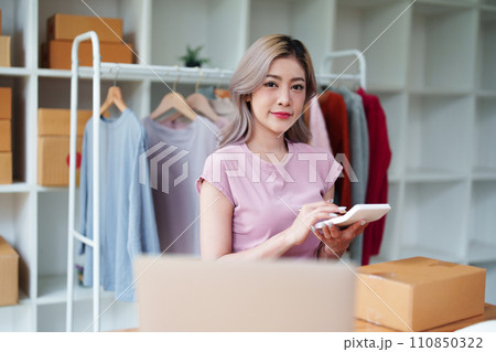 Portrait Of Asian Female Owner Of Fashion Store Checking Stock In Clothing Store With using notebook successful happy smile at small business, sme or ecommerce concepts. 110850322