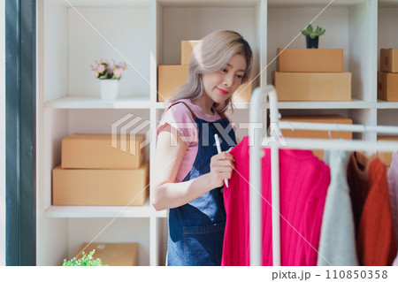 Portrait Of Asian Female Owner Of Fashion Store Checking Stock In Clothing Store With using notebook successful happy smile at small business, sme or ecommerce concepts. 110850358