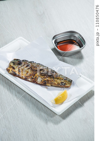 Fried mackerel with lemon and soy sauce on white plate 110850476