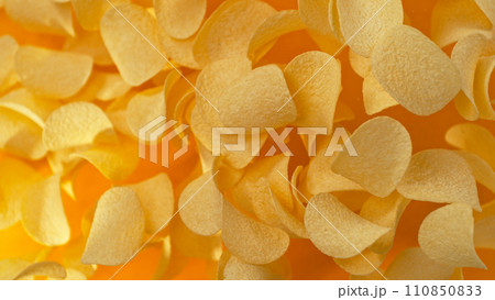 Freeze motion of flying fried potatoes chips on yellow background Freeze motion of flying fried potatoes chips on yellow background 110850833