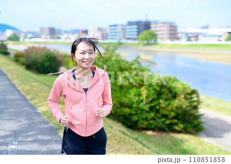 川沿いの道をジョギングする若い女性　ダイエット　ランニングウェア　 110851858