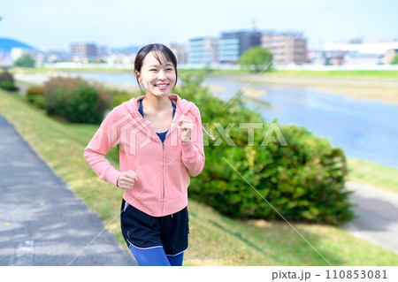 川沿いの道をジョギングする若い女性　ダイエット　ランニングウェア 110853081