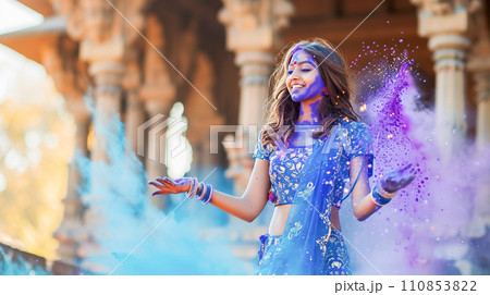 AI-generated content. A young girl in the national festive attire of a sari dances joyfully among clouds of blue Holi powder against 110853822