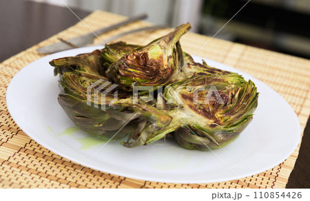 Cooked fried halves artichokes on white plate 110854426