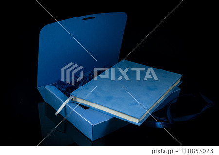 Best gift for men. Man gift concept. Blue notebook with navy blue gift box on black background. Copy space text. Valentine's day, wedding, birthday and special occasion gift concept. Copy space text. 110855023