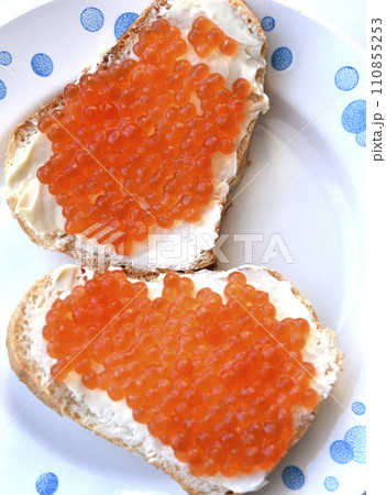Red salmon caviar on bread and butter. A sandwich with caviar and butter on a plate. Red salmon caviar on bread and butter. A sandwich with caviar and butter on a plate. 110855253