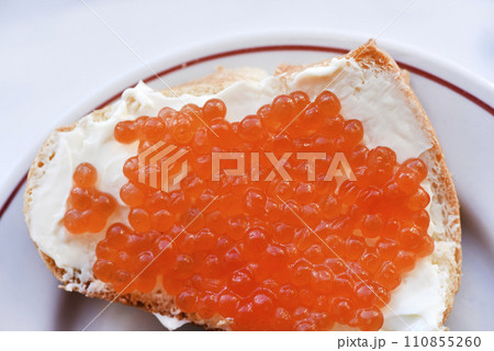 Red salmon caviar on bread and butter. A sandwich with caviar and butter on a plate. Red salmon caviar on bread and butter. A sandwich with caviar and butter on a plate. 110855260