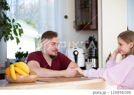 A couple in love sits across from each other and looks deeply into each other's eyes. 110856109