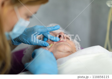 The cosmetologist works with disposable gloves and a surgical mask. 110856115