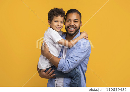 Happy black father lifting his little son and hugging Happy black father lifting his little son and hugging 110859482