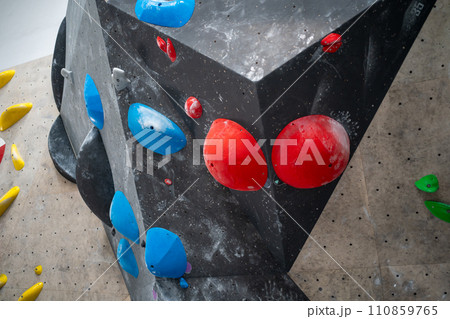 Red and blue grips on black artificial wall 110859765