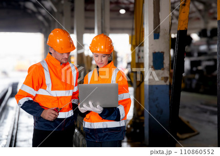 Young caucasian engineer man and woman checking train with laptop in station. 110860552