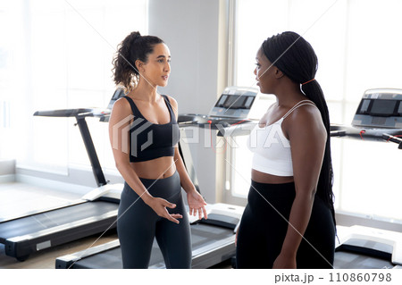 Two young woman talking in the gym, woman in sportswear and friend or coach relax. 110860798