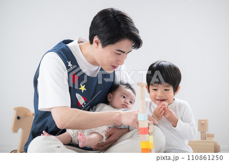 男性保育士の転職採用イメージ　室内で積み木で遊ぶ笑顔の保育士と幼児 110861250