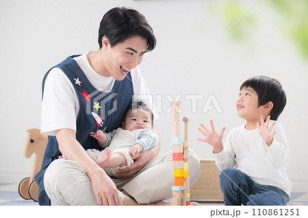 男性保育士の転職採用イメージ　室内で積み木で遊ぶ笑顔の保育士と幼児 110861251