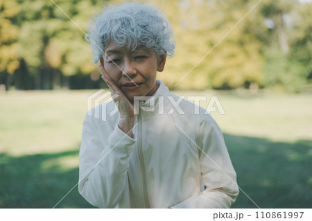 歯が痛む公園の60代女性 歯が痛む公園の60代女性 110861997